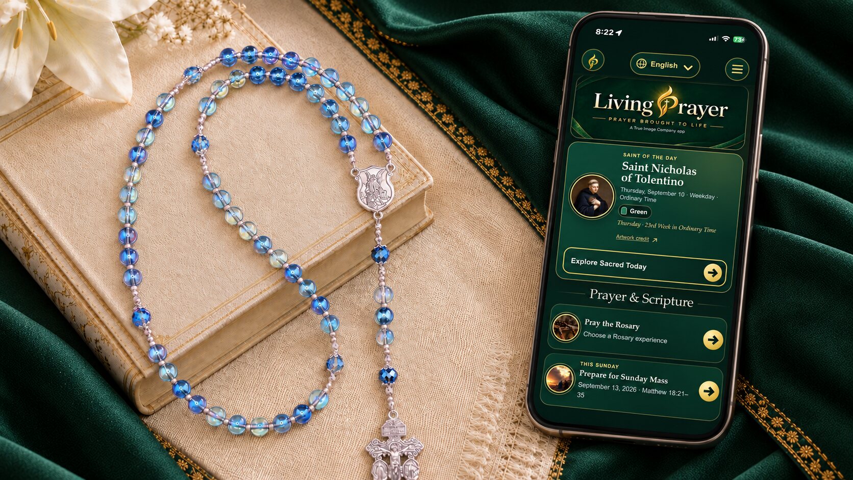 Living Prayer app displayed beside a handmade blue rosary on an emerald and gold prayer setting